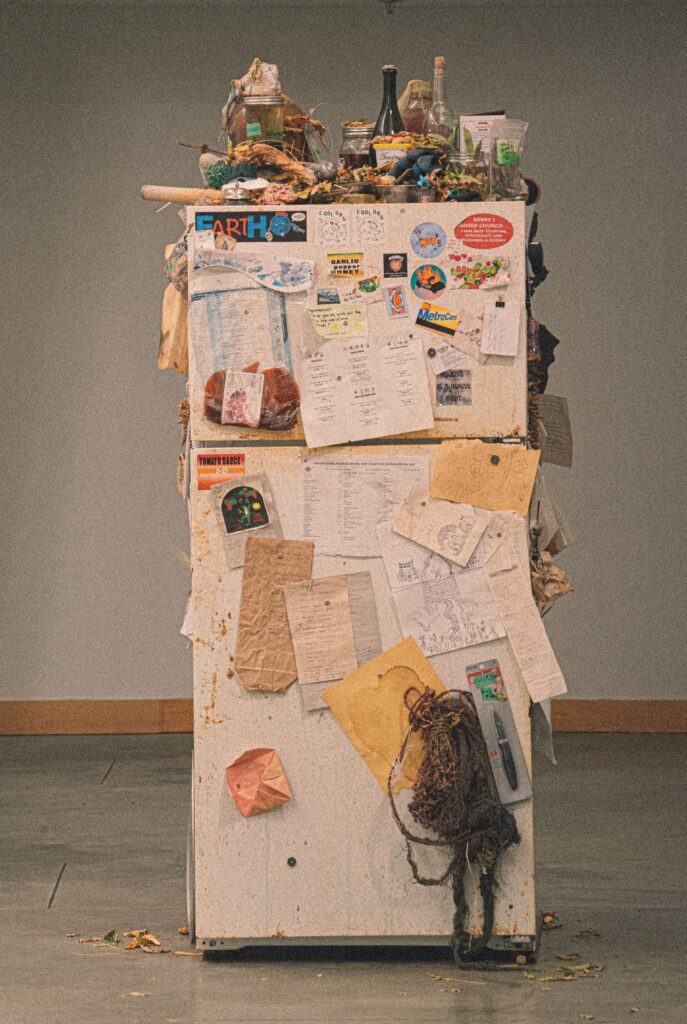 An artistic portrayal of a cluttered fridge populated with notes and small items.