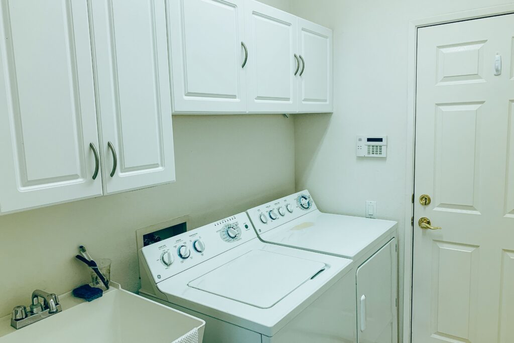 Well-organized laundry space with a washing machine, dryer, and white cabinets,