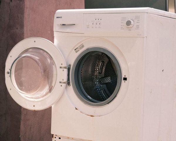 Outdoor view of two stacked laundry machines with an open door, showing rustic surroundings, Winston-Salem appliance repair